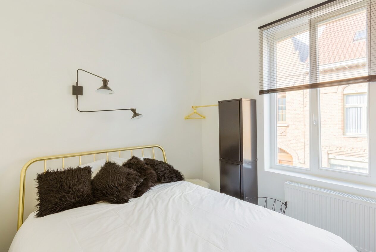 Slaapkamer met messing bed en wandlamp