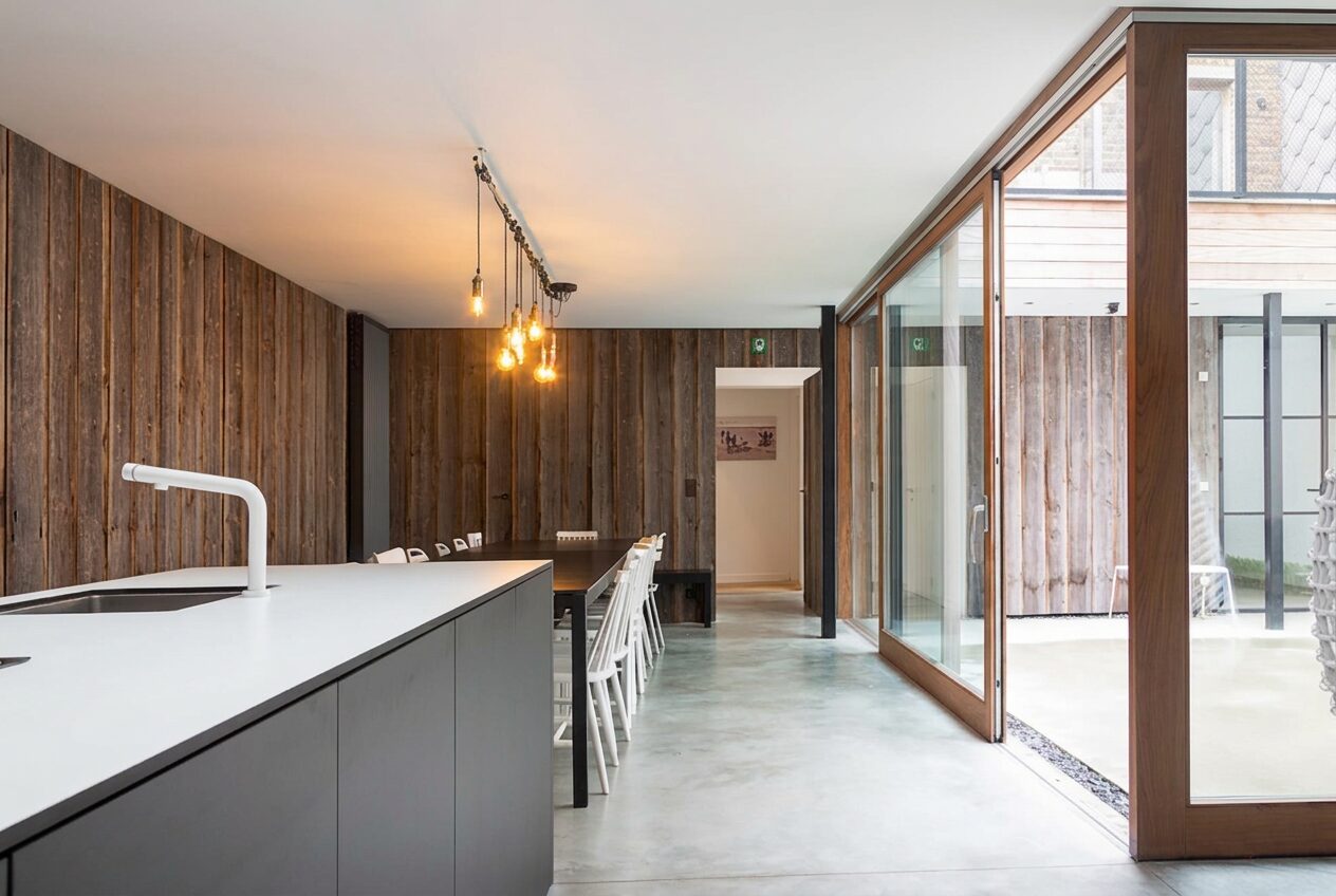 Open keuken met kookeiland, houten wand en betonvloer